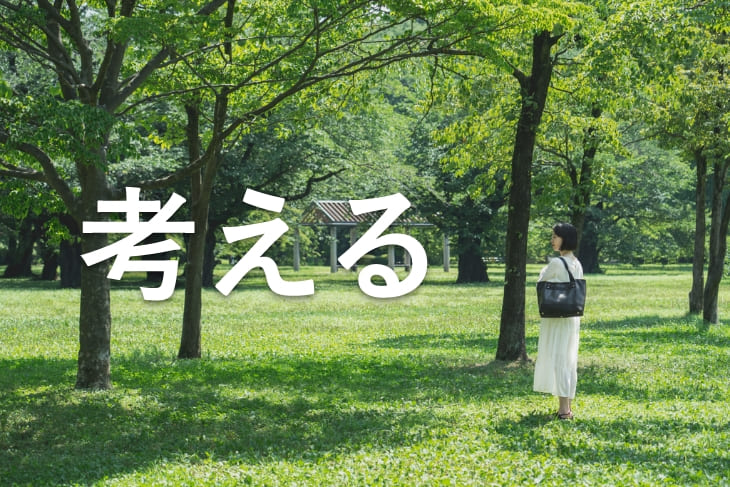 「考える」という文字と新緑の公園と白いワンピースを着た女性